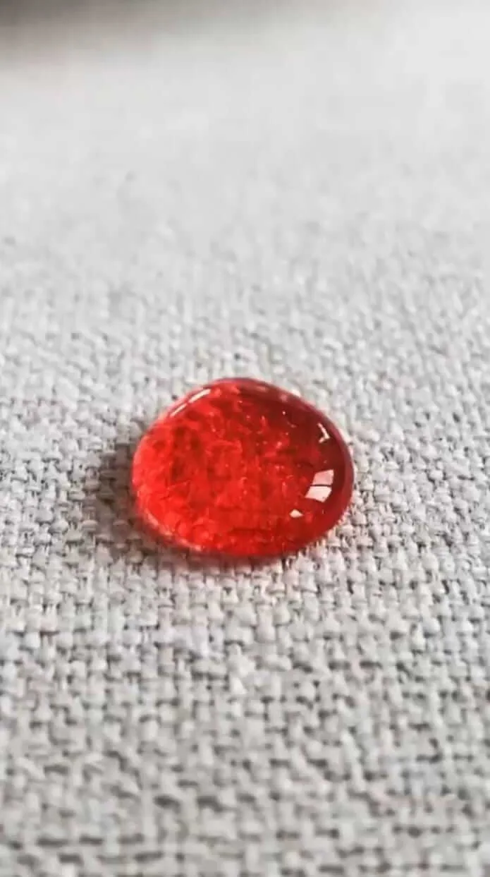 Gota de líquido vermelha sobre tecido claro impermeabilizado.