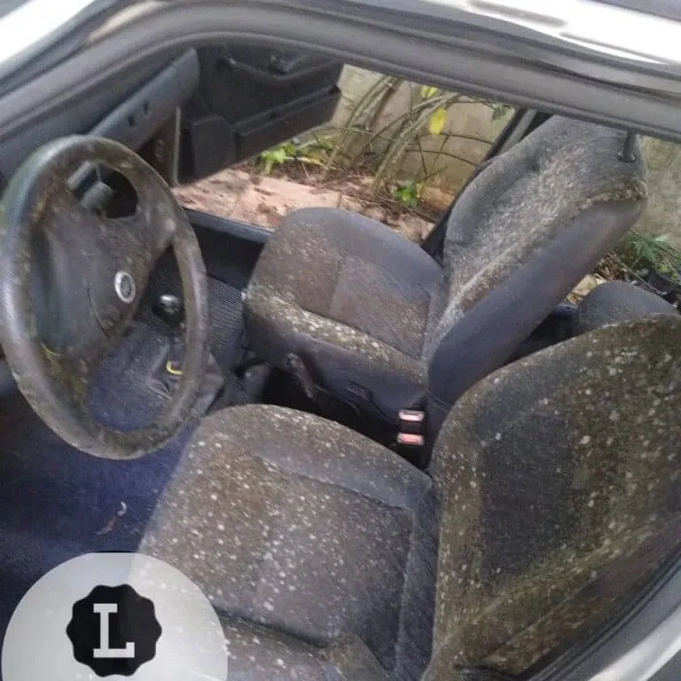Interior de veículo sujo com manchas e detritos.