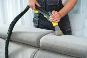 Especialista da Lava Tudo VIP usando equipamento de limpeza a vapor para remover manchas de um sofá retrátil cinza, ilustrando a excelência e a eficácia do serviço da empresa.