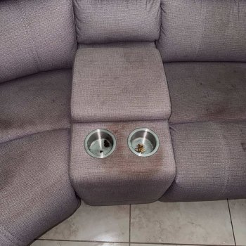Sofá com manchas e restos de sujeira nos suportes de copo.